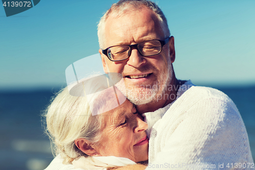 Image of happy senior couple hugging on summer beach