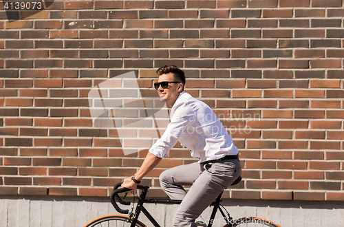 Image of young man riding bicycle on city street