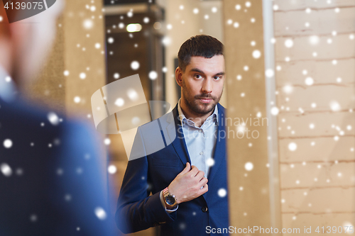 Image of man trying jacket on at mirror in clothing store