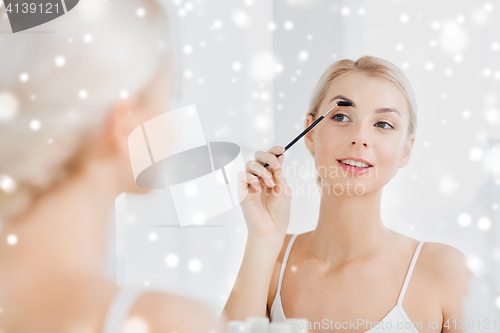 Image of woman brushing eyebrow with brush at bathroom