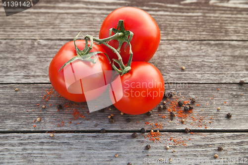 Image of Dewy red tomatoes with pepper on old wood