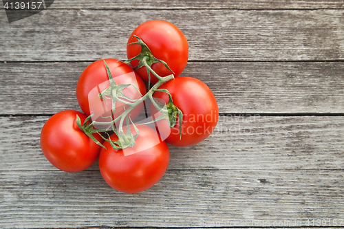 Image of Dewy red tomatoes on the rustic wood