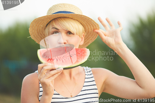 Image of Beautiful girl in straw hat eating fresh watermelon. Film camera style