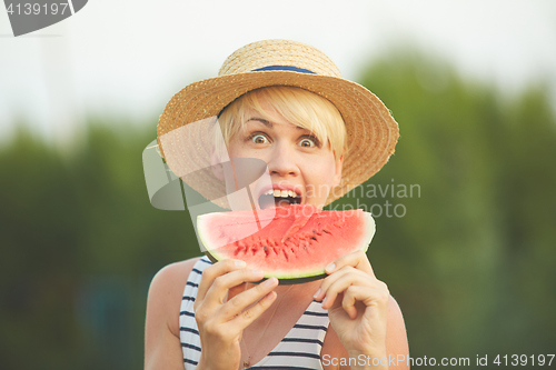 Image of Beautiful girl in straw hat eating fresh watermelon. Film camera style