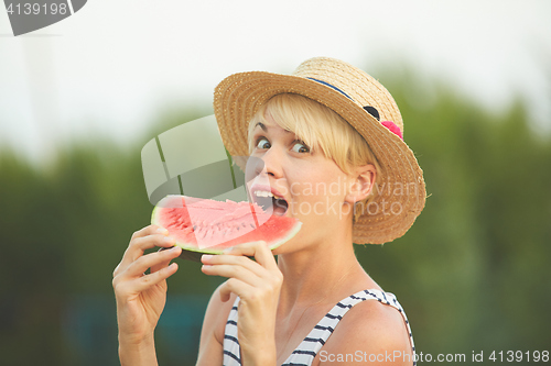 Image of Beautiful girl in straw hat eating fresh watermelon. Film camera style