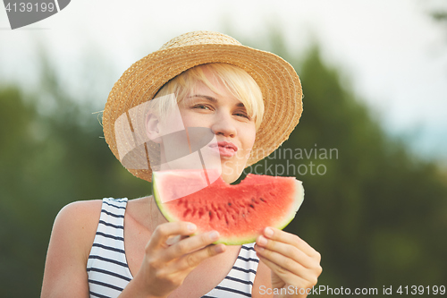 Image of Beautiful girl in straw hat eating fresh watermelon. Film camera style