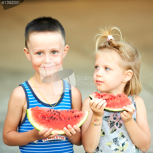 Image of Young girl and boy eating watermelon