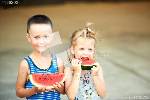 Image of Young girl and boy eating watermelon