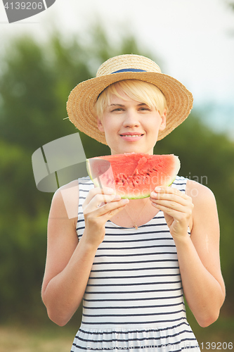 Image of Beautiful girl in straw hat eating fresh watermelon. Film camera style