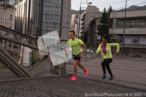 Image of young multiethnic couple jogging in the city