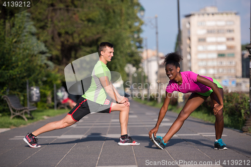 Image of jogging couple warming up and stretching in the city