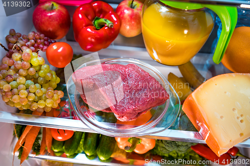 Image of Fresh raw meat on a shelf open refrigerator