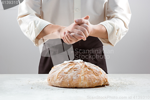 Image of The male hands in flour and rustic organic loaf of bread