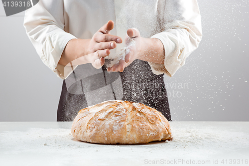 Image of The male hands in flour and rustic organic loaf of bread