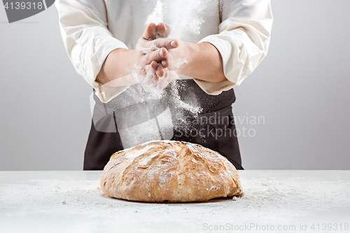 Image of The male hands in flour and rustic organic loaf of bread