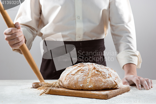 Image of The male hands and rustic organic loaf of bread