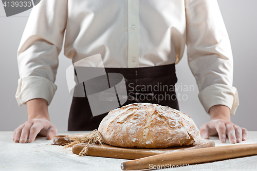 Image of The male hands and rustic organic loaf of bread