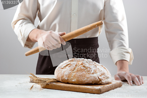 Image of The male hands and rustic organic loaf of bread