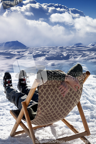 Image of Skier at winter mountains resting on sun-lounger