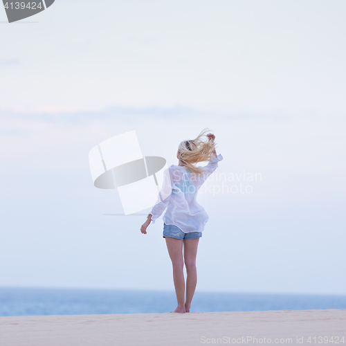 Image of Woman on sandy beach in white shirt.