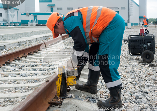 Image of Worker establishes hydraulic jack for lifting rail