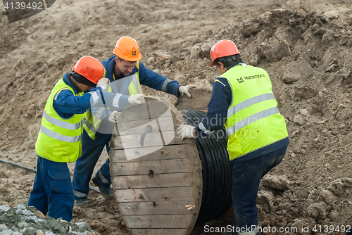 Image of Workers pulling roll high voltage cable line