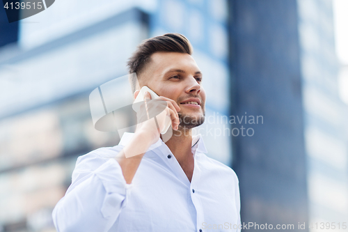 Image of happy man with smartphone calling on city street