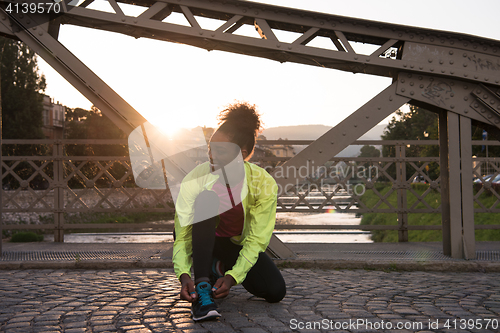 Image of African american woman runner tightening shoe lace