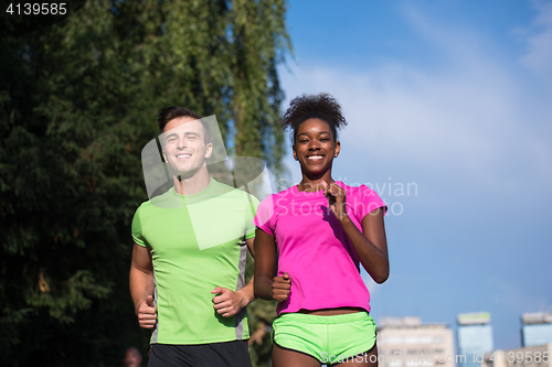 Image of young smiling multiethnic couple jogging in the city