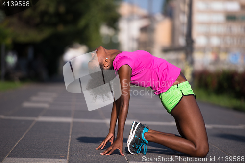 Image of sporty young african american woman stretching outdoors
