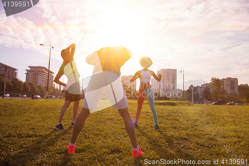 Image of multiethnic group of people stretching in city park