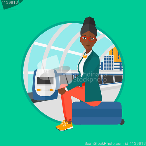 Image of Woman sitting on suitcase at the train station.