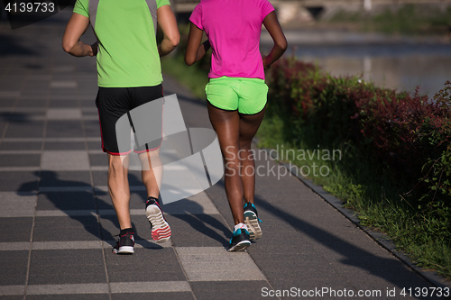 Image of young smiling multiethnic couple jogging in the city