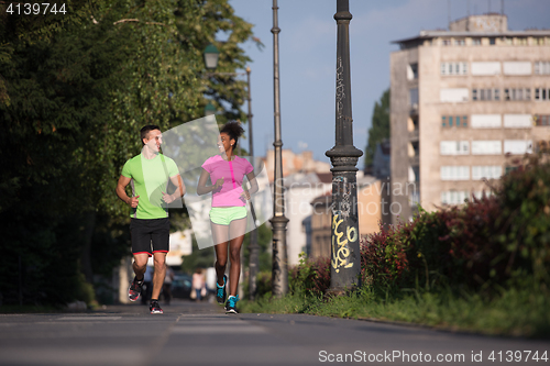 Image of young smiling multiethnic couple jogging in the city