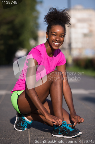 Image of African american woman runner tightening shoe lace