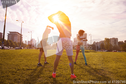 Image of multiethnic group of people stretching in city park