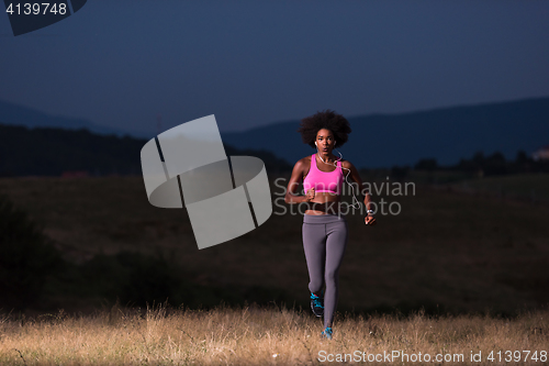 Image of Young African american woman jogging in nature