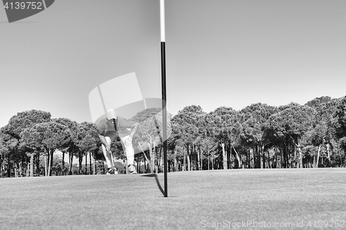 Image of golf player hitting shot with club on course