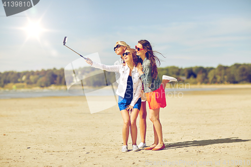 Image of group of smiling women taking selfie on beach