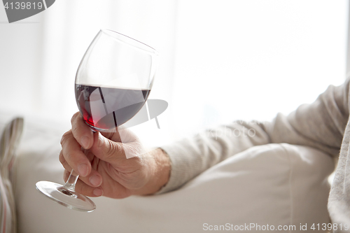 Image of close up of hand holding glass with red wine