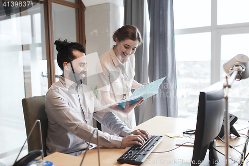 Image of happy creative team with computer in office