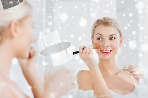 Image of woman with makeup brush and powder at bathroom