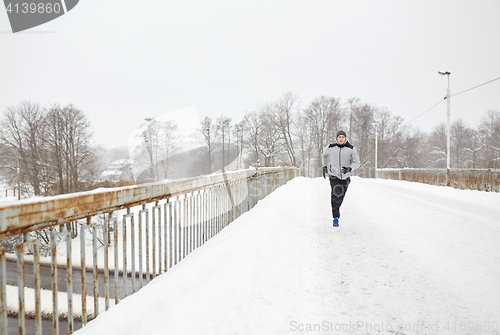 Image of man running along snow covered winter bridge road