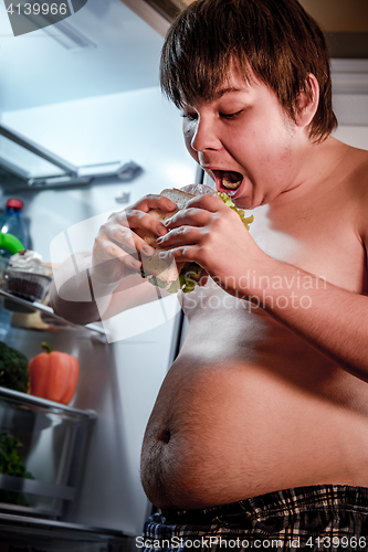 Image of Hungry man holding a sandwich in his hands and standing next to 