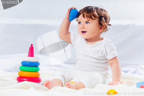 Image of Happy baby boy sitting with toy