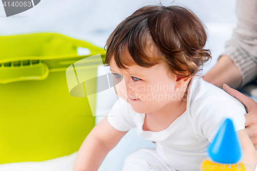Image of Happy baby boy sitting with toy