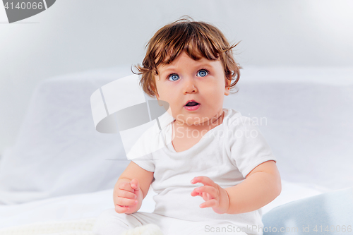 Image of Happy baby boy sitting on gray