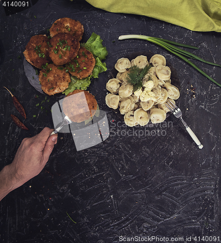 Image of Fried cutlets and russian pelmeni on black background