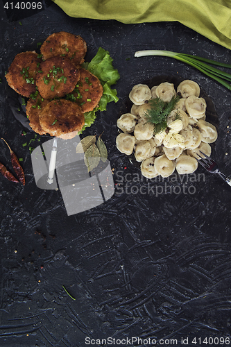 Image of Fried cutlets and russian pelmeni on black background