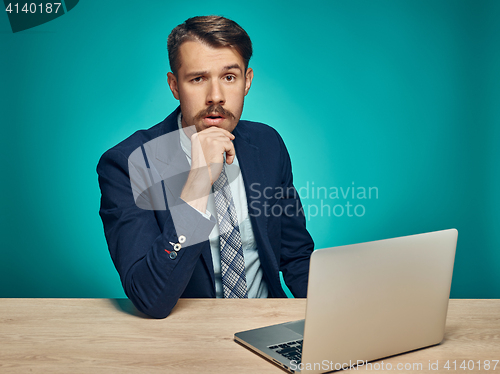 Image of Sad Young Man Working On Laptop At Desk